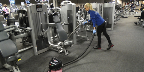 Woman cleaning stationary bike in fitness center